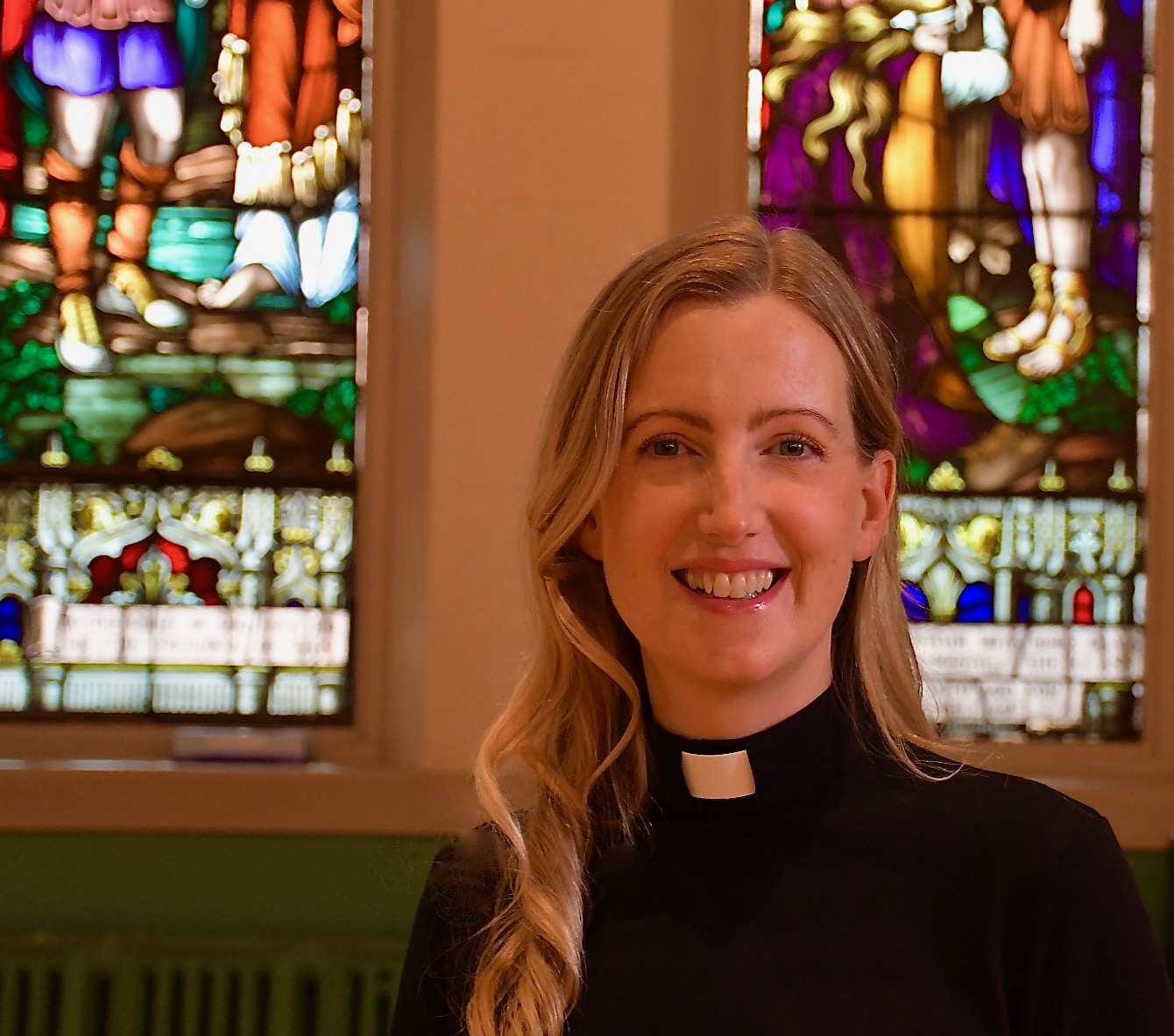 Photo of curate Hannah Johnson with stained glass in the background